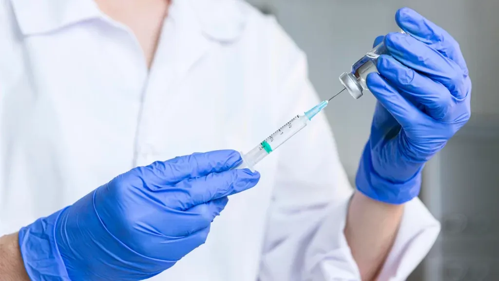 Clinician in gloves preparing a syringe